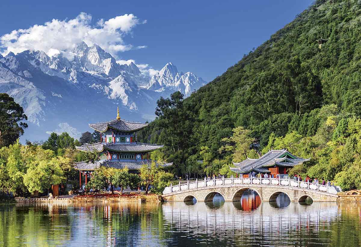 templo en china con paisaje lleno de arboles sobre un lado, de fondo se ven montanas con nieve
